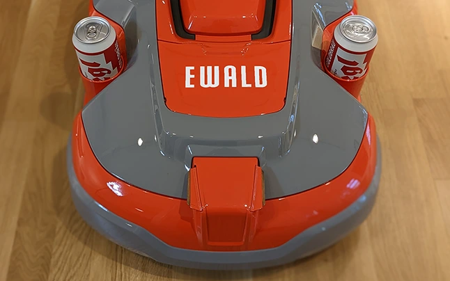 Foto eines grau/roten Rasenmähroboters mit der Aufschrift 'Ewald'